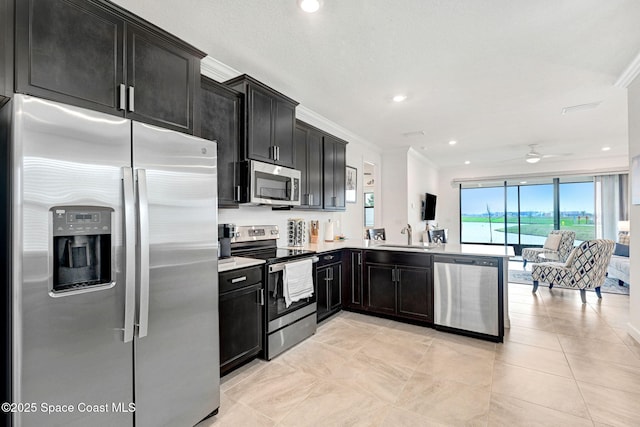kitchen with open floor plan, stainless steel appliances, dark cabinetry, and crown molding