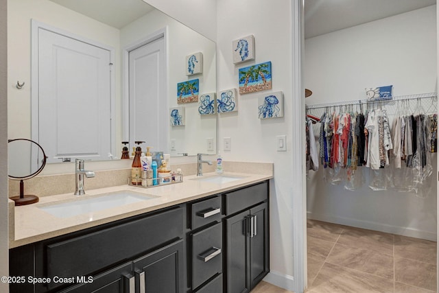 full bathroom with baseboards, double vanity, a sink, and tile patterned floors