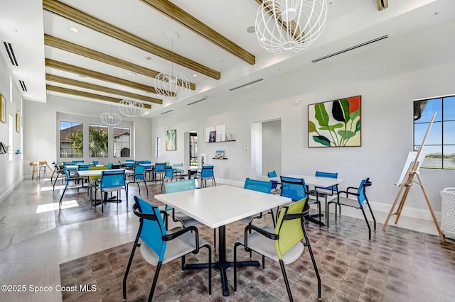 dining area featuring visible vents, a towering ceiling, baseboards, beam ceiling, and an inviting chandelier