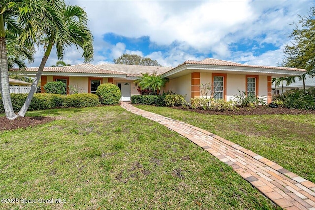 single story home featuring a tiled roof, a front lawn, and stucco siding