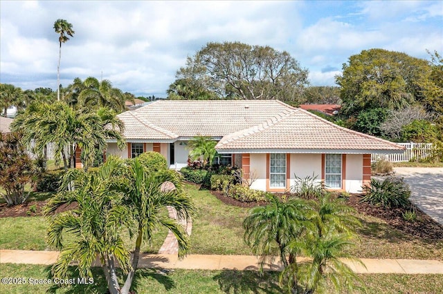 single story home featuring a tile roof, a front yard, fence, and stucco siding