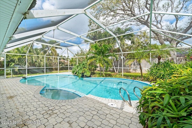 view of pool featuring glass enclosure, a pool with connected hot tub, and a patio area