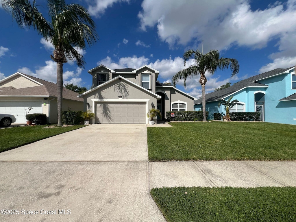 traditional-style house featuring a garage, driveway, a front yard, and stucco siding