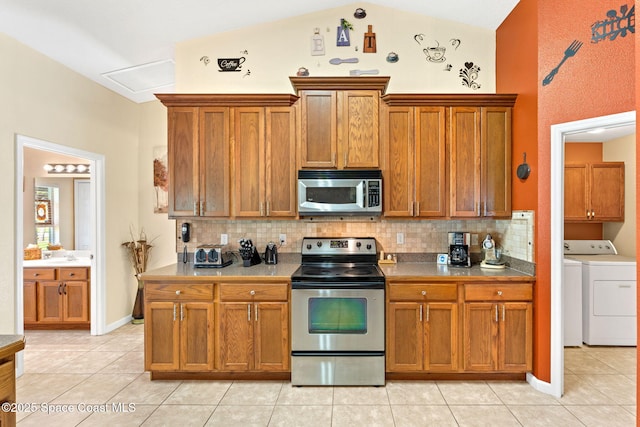 kitchen with lofted ceiling, stainless steel appliances, tasteful backsplash, and washer and clothes dryer