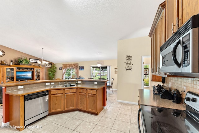 kitchen featuring lofted ceiling, hanging light fixtures, appliances with stainless steel finishes, and brown cabinetry