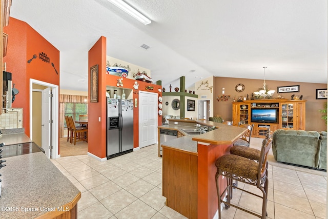 kitchen with stainless steel appliances, a breakfast bar, a sink, open floor plan, and vaulted ceiling