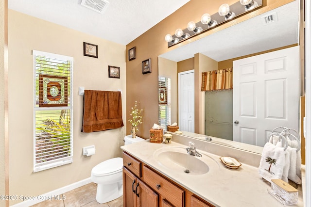 bathroom featuring visible vents, toilet, vanity, baseboards, and tile patterned floors