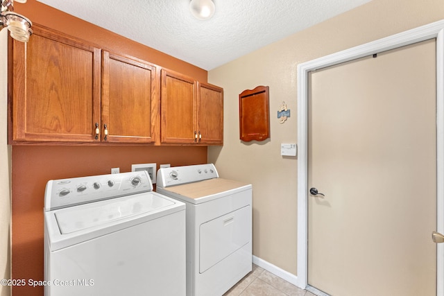 washroom featuring light tile patterned floors, cabinet space, washing machine and dryer, a textured ceiling, and baseboards