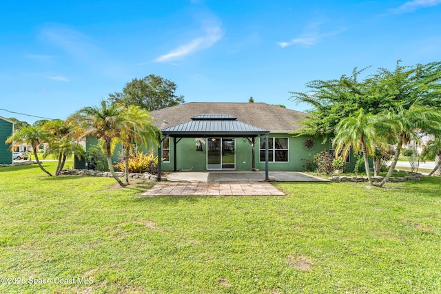 rear view of house featuring stucco siding, a lawn, a patio, and a gazebo