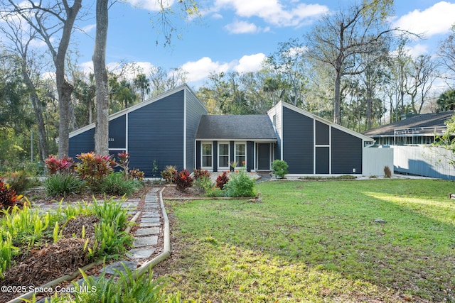 back of property featuring a shingled roof, a lawn, and fence