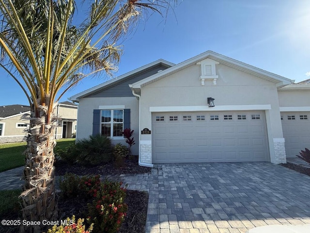 view of front of home with stucco siding, decorative driveway, and a garage