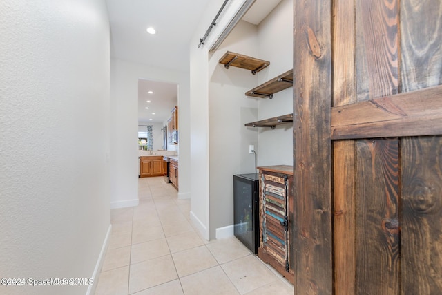 corridor featuring light tile patterned floors, a barn door, baseboards, and recessed lighting