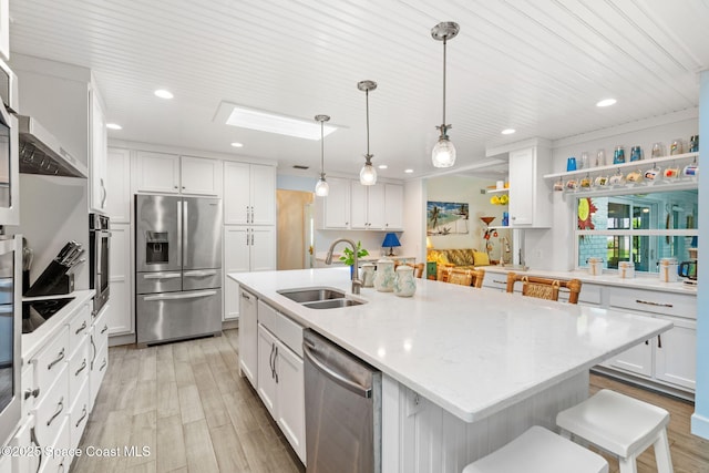 kitchen with a sink, light wood-style flooring, appliances with stainless steel finishes, and white cabinetry
