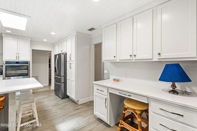 kitchen featuring built in desk, recessed lighting, white cabinetry, visible vents, and stainless steel appliances