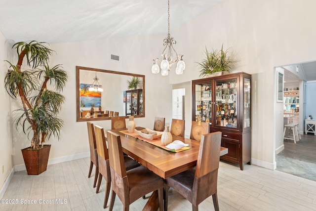 dining room with visible vents, baseboards, high vaulted ceiling, and an inviting chandelier