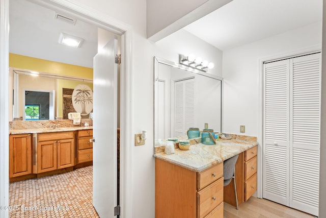 bathroom with a closet, vanity, and visible vents