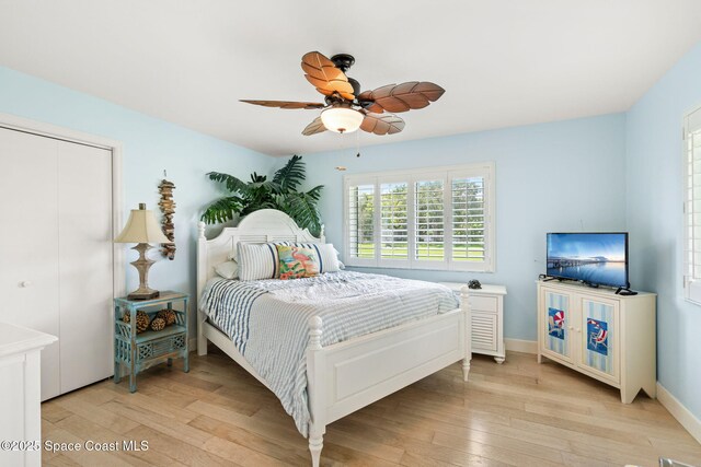bedroom with a closet, baseboards, light wood-type flooring, and a ceiling fan