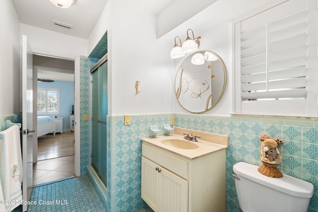 ensuite bathroom featuring visible vents, tile walls, tile patterned flooring, a wainscoted wall, and a stall shower