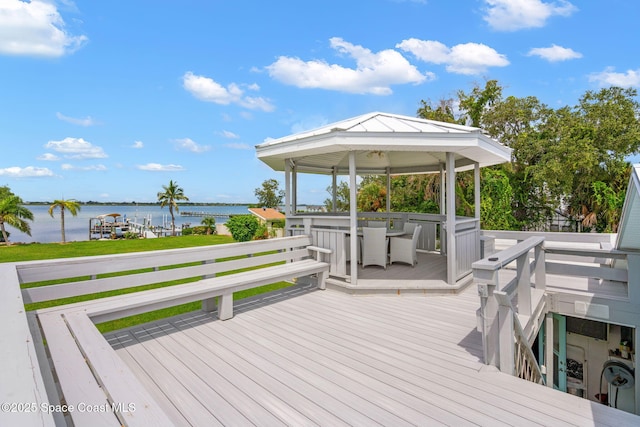 deck with a gazebo, outdoor dining area, and a water view