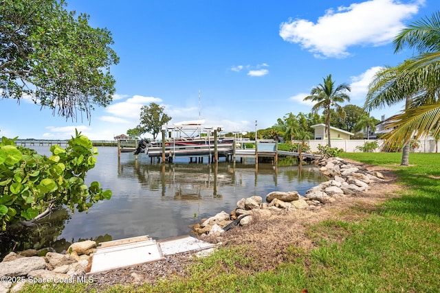 view of dock with a water view, fence, and a yard