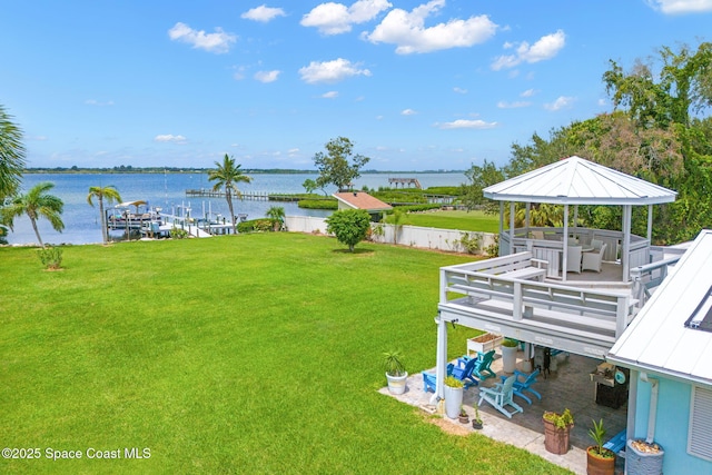 view of yard with a water view, a boat dock, a gazebo, and fence