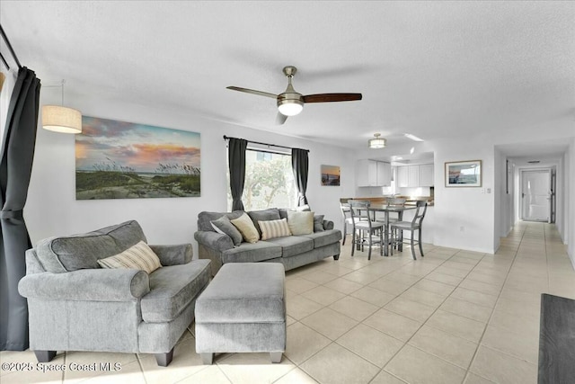 living room with a textured ceiling, a ceiling fan, and light tile patterned flooring