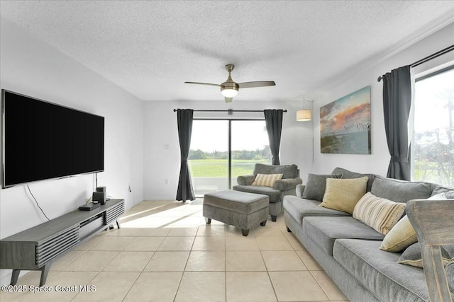 living room featuring ceiling fan, a textured ceiling, light tile patterned flooring, and a wealth of natural light