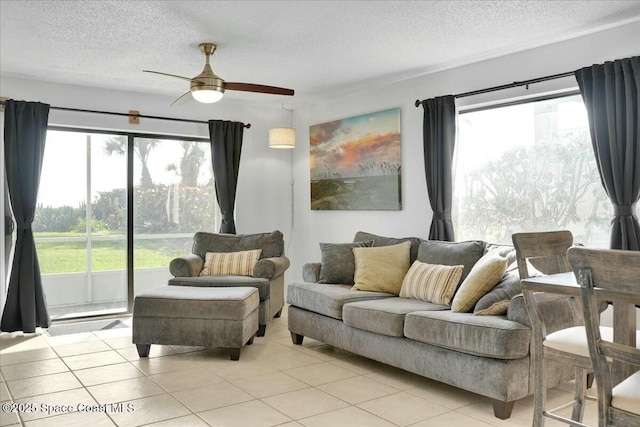 living room with light tile patterned flooring, ceiling fan, and a textured ceiling