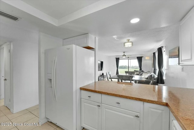 kitchen with white cabinets, white fridge with ice dispenser, visible vents, and open floor plan