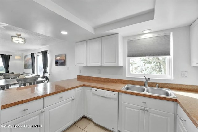 kitchen with a sink, white cabinets, open floor plan, light countertops, and dishwasher