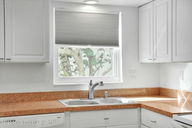 kitchen with light countertops, white cabinets, a sink, and dishwasher