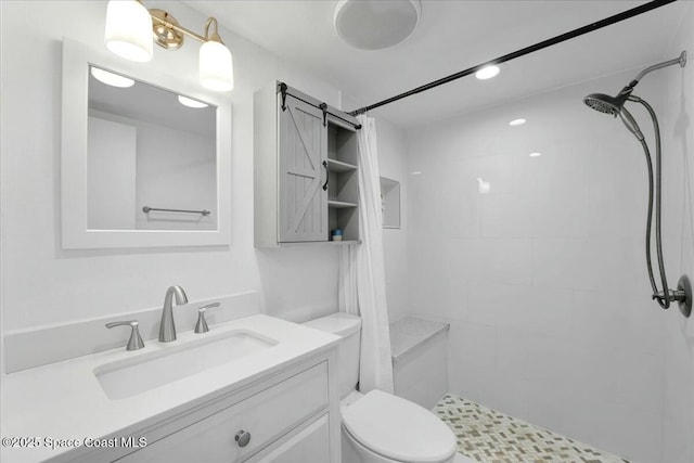 bathroom with toilet, tiled shower, and vanity