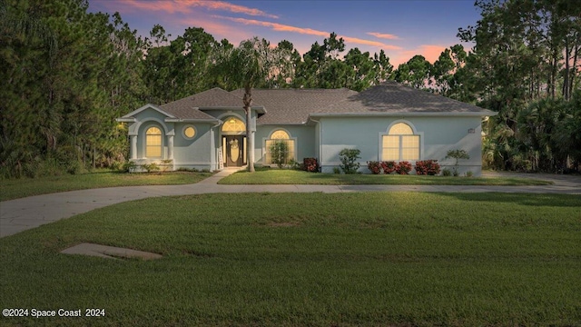 mediterranean / spanish house featuring stucco siding, driveway, and a lawn