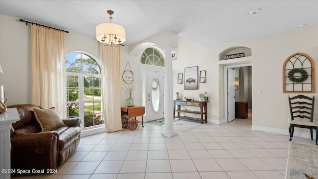 foyer featuring a chandelier, a textured ceiling, light tile patterned flooring, and baseboards