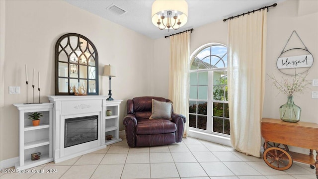 living area featuring a glass covered fireplace, visible vents, an inviting chandelier, and light tile patterned flooring