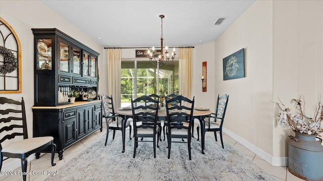 dining space with light tile patterned floors, baseboards, visible vents, and an inviting chandelier