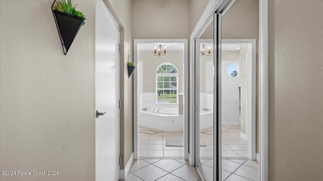 hallway with light tile patterned floors and a notable chandelier