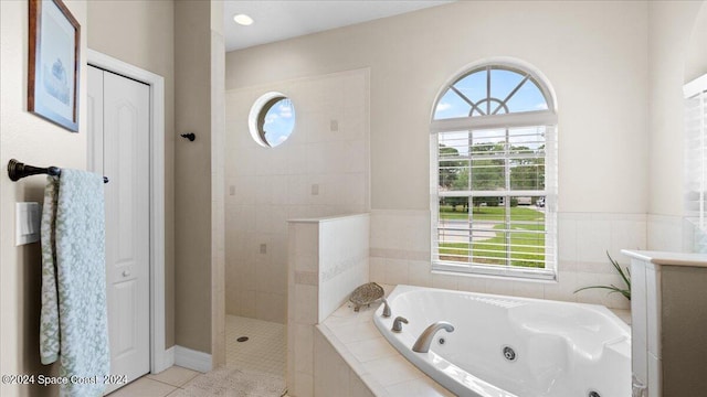 bathroom with tile patterned flooring, a tub with jets, walk in shower, and a closet