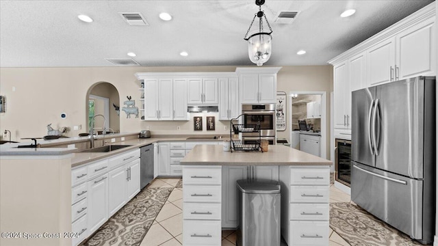 kitchen with light countertops, hanging light fixtures, appliances with stainless steel finishes, a sink, and a peninsula