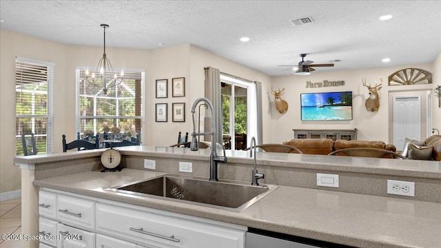 kitchen featuring open floor plan, white cabinets, a sink, and decorative light fixtures