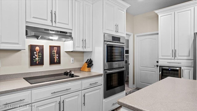 kitchen featuring light countertops, stainless steel double oven, white cabinetry, under cabinet range hood, and black electric cooktop