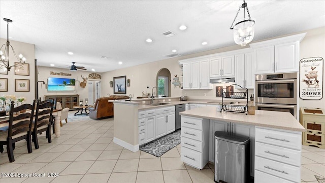 kitchen with open floor plan, a peninsula, hanging light fixtures, light countertops, and white cabinetry