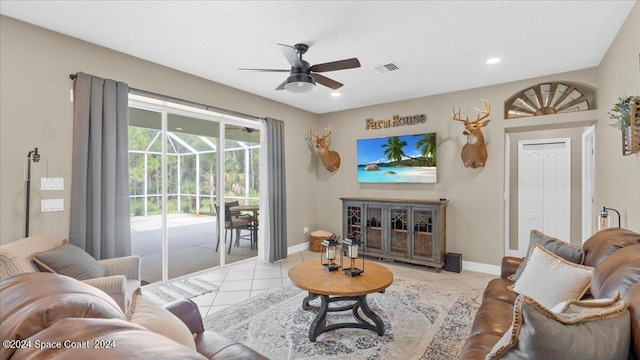 living area with a textured ceiling, light tile patterned flooring, a sunroom, and baseboards