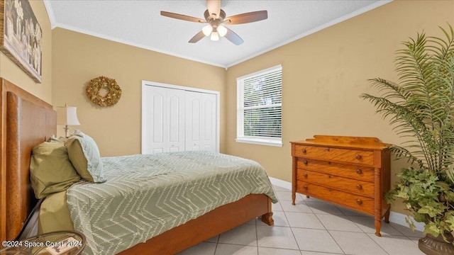 bedroom featuring light tile patterned floors, a closet, ornamental molding, ceiling fan, and baseboards