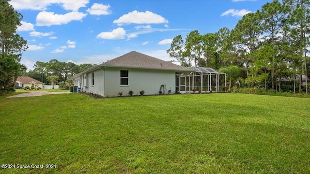 back of property with glass enclosure, central AC, a lawn, and stucco siding