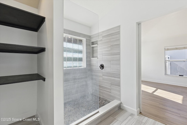 full bathroom featuring wood finished floors, baseboards, and a walk in shower