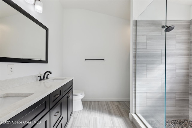 bathroom featuring toilet, a sink, baseboards, double vanity, and walk in shower