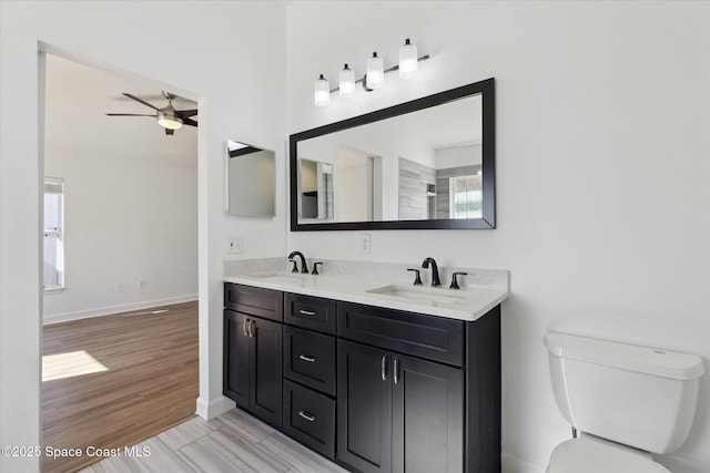 full bath with double vanity, ceiling fan, toilet, and a sink