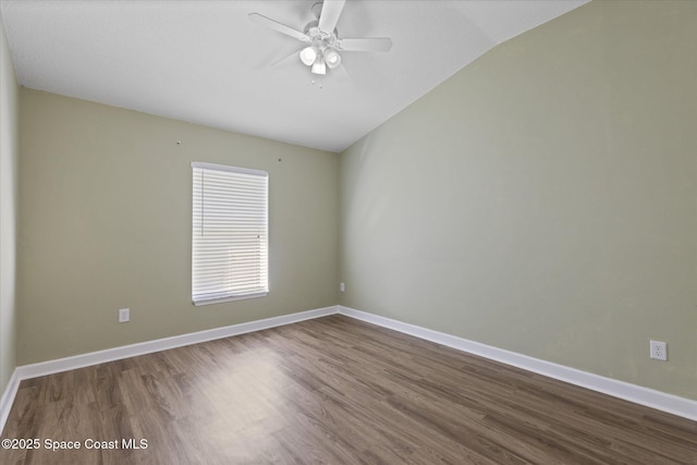 spare room with ceiling fan, baseboards, vaulted ceiling, and wood finished floors