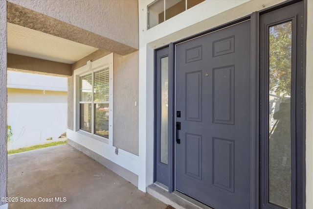 doorway to property featuring stucco siding